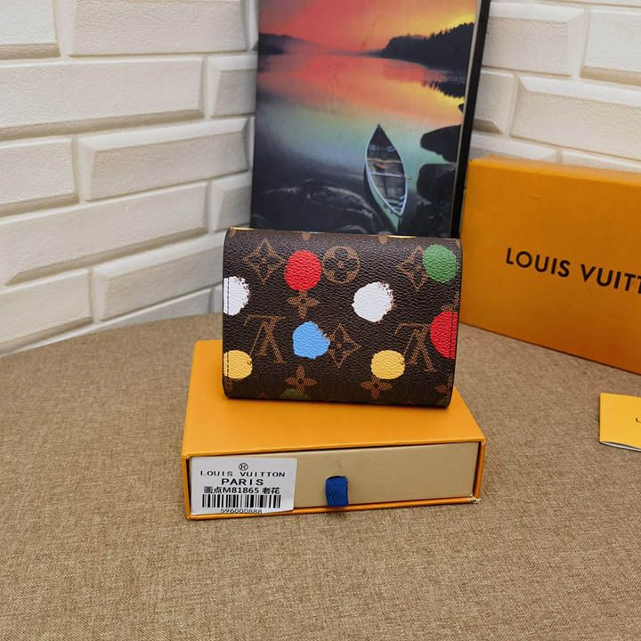 ルイヴィトン | LV×YK Victorine×草間彌生コラボシリーズのウォレットです。日本人アーティストの創作活動を通じて使われてきた水玉模様を、今回はモノグラム・キャンバスにまるで手描きのように表現し、芸術的な味わいを持った機能的なデザインに昇華させました。 寸法: 12 × 9.5 × 1.5 cm